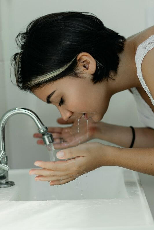 Kobieta myjąca twarz w umywalce