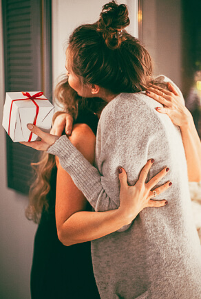 Dwie kobiety przytulające się podczas wymiany prezentów